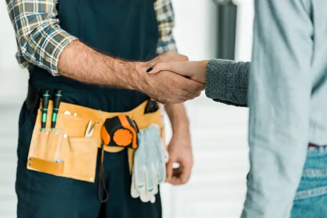 plumber shaking hand with customer in kitchen - Wrench It Up plumbing and mechanical